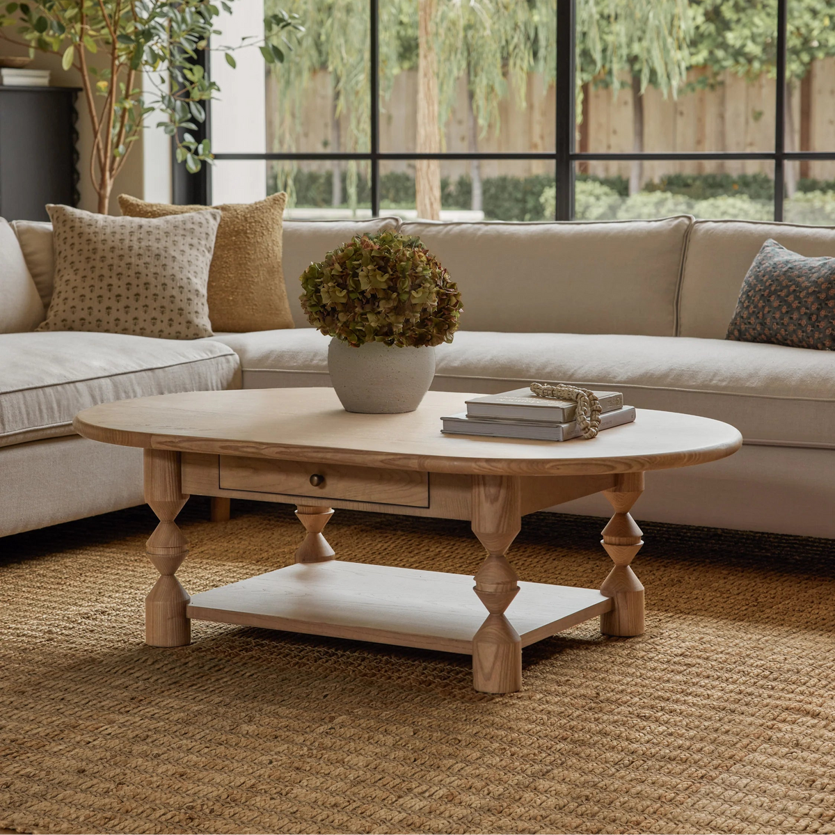Living room with a wooden coffee table, beige sofa, and large windows.