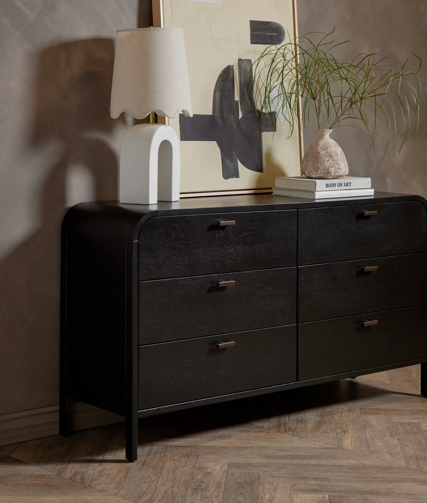 Black dresser with decorative items against a textured wall