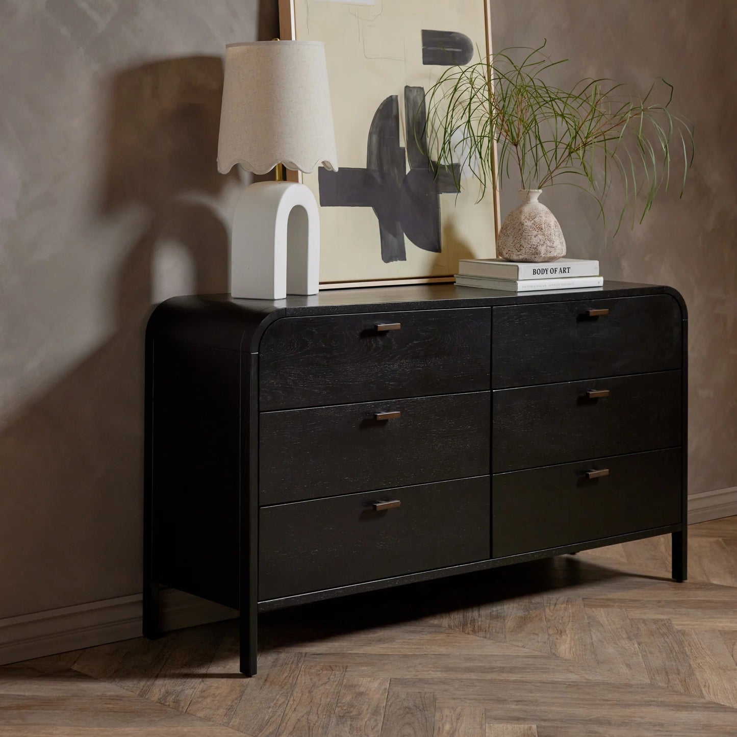 Black dresser with decorative items against a textured wall
