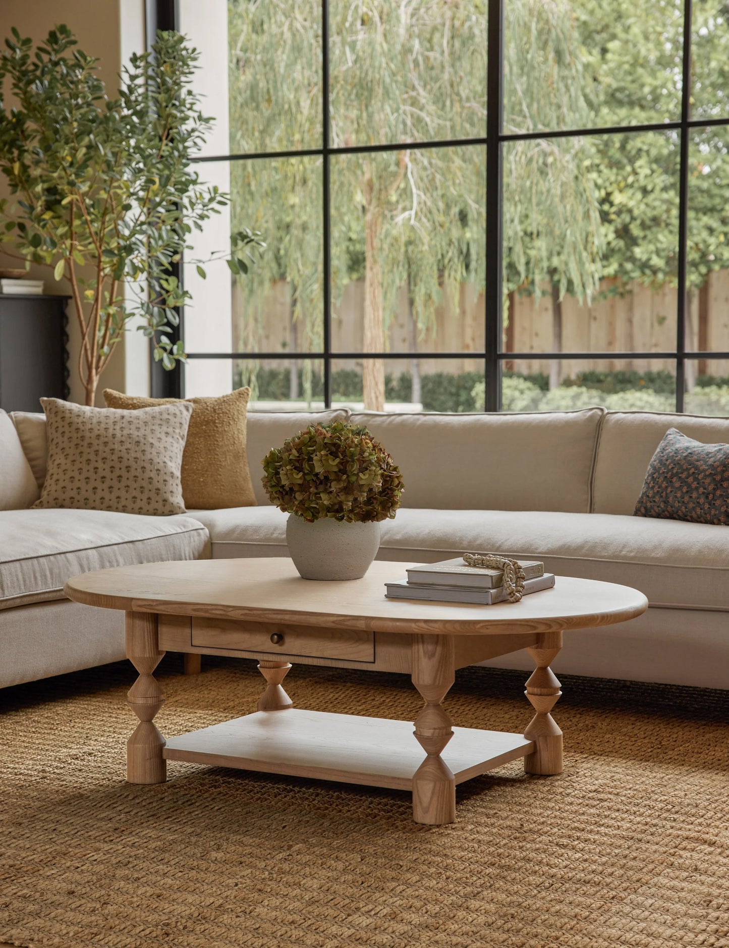 Living room with a wooden coffee table, beige sofa, and large windows.