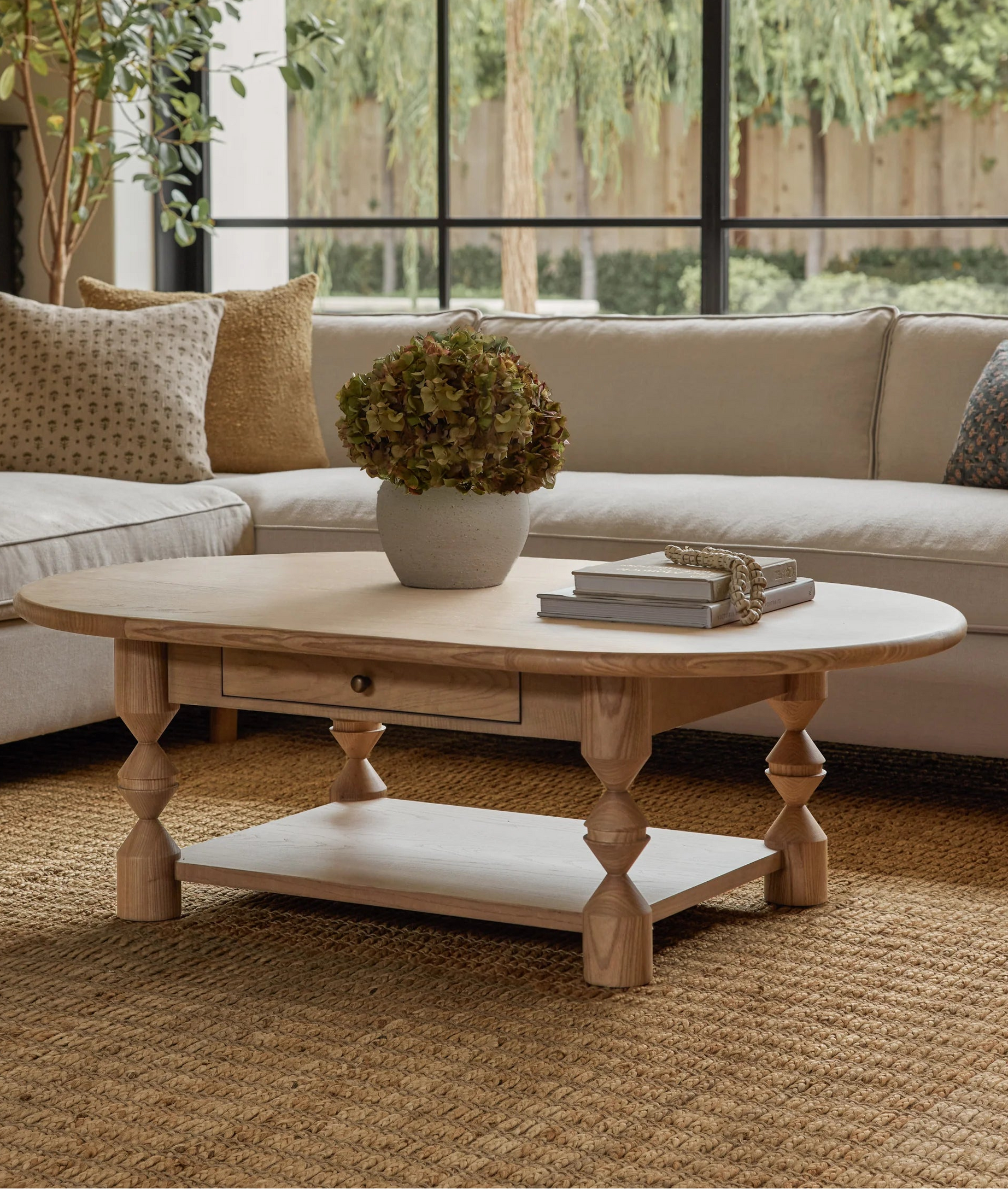 Living room with a wooden coffee table, beige sofa, and large windows.