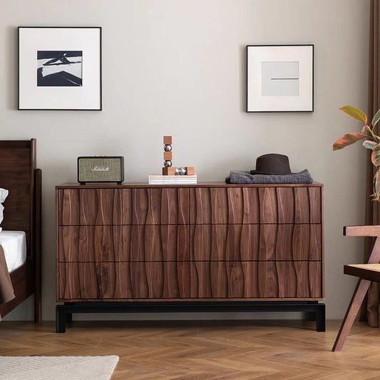 Wooden dresser in a room with framed art on the wall and a plant.